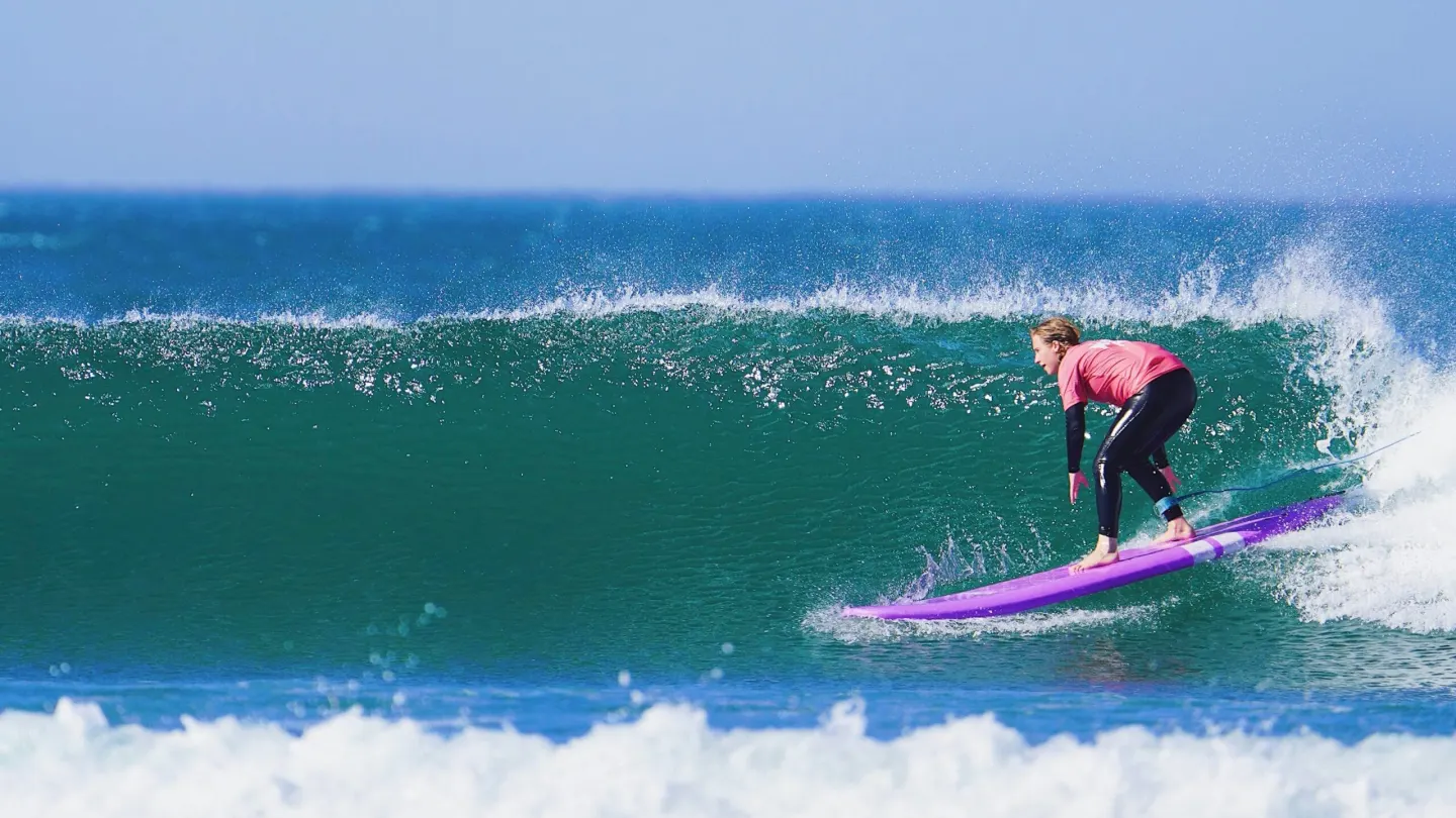 A surfer riding across a clean turquoise wave