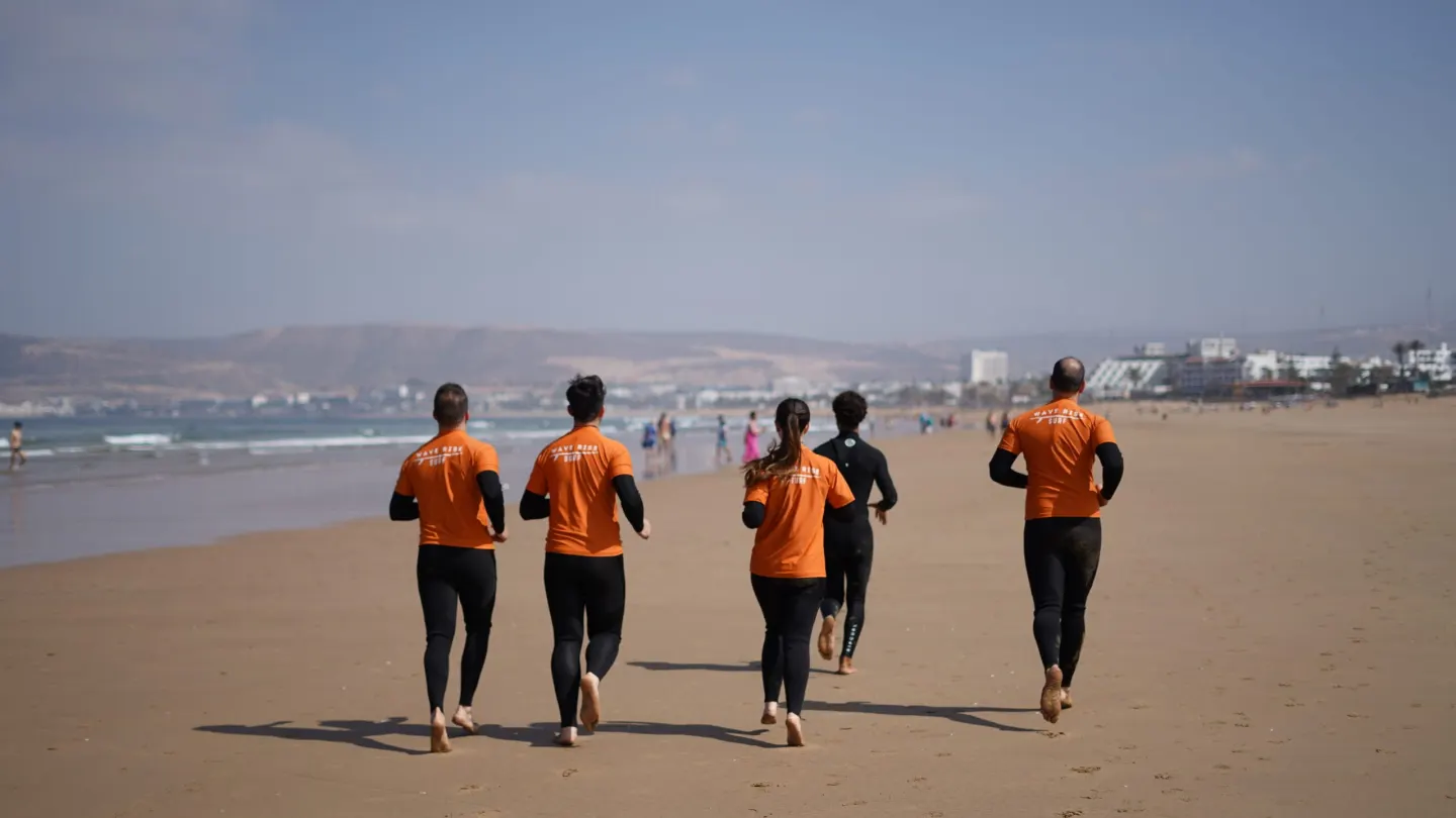 Surfers in wetsuits walking down the beach in Agadir